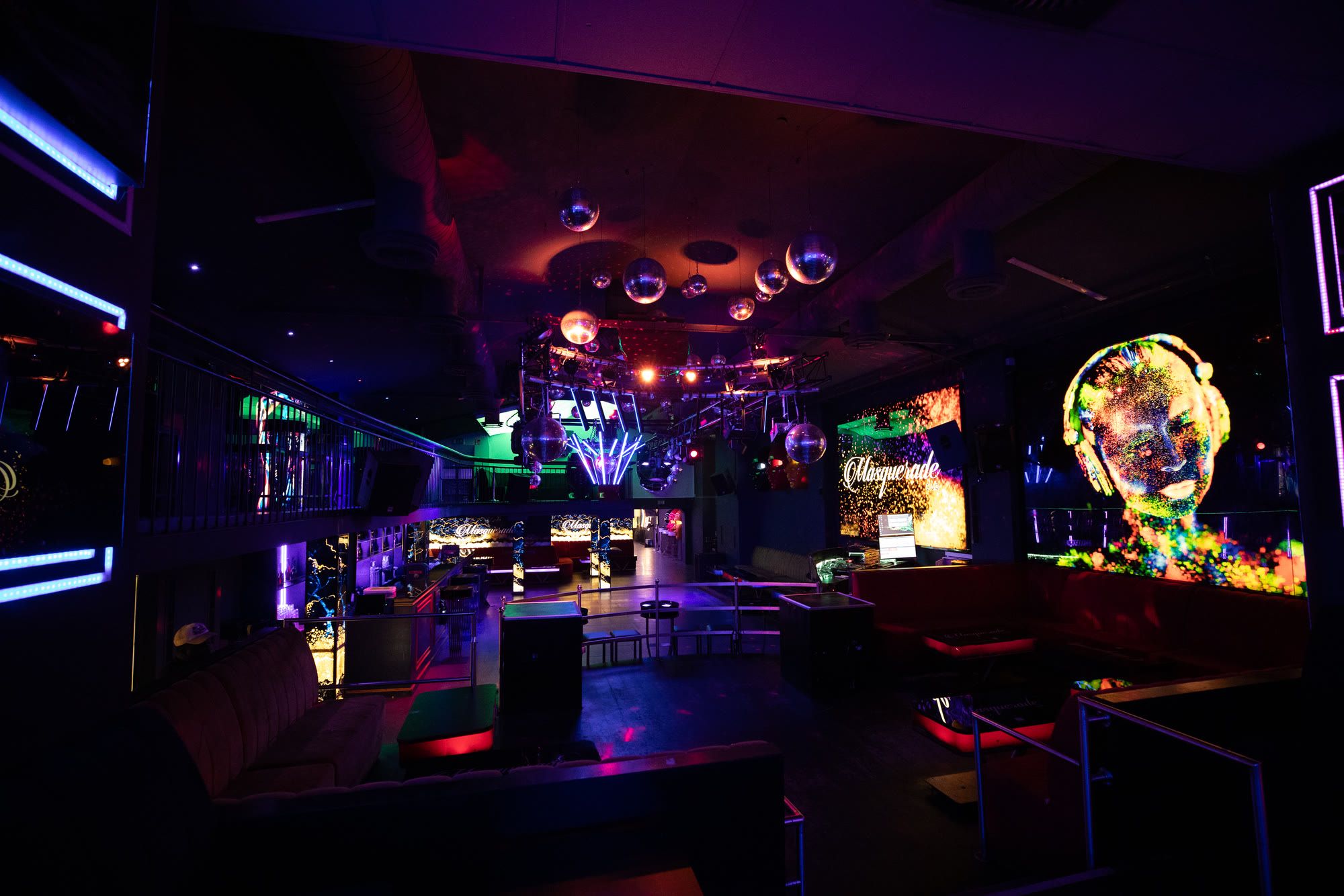 Blick durch den Hauptraum mit Discokugeln, Masken-Kunst und Empore